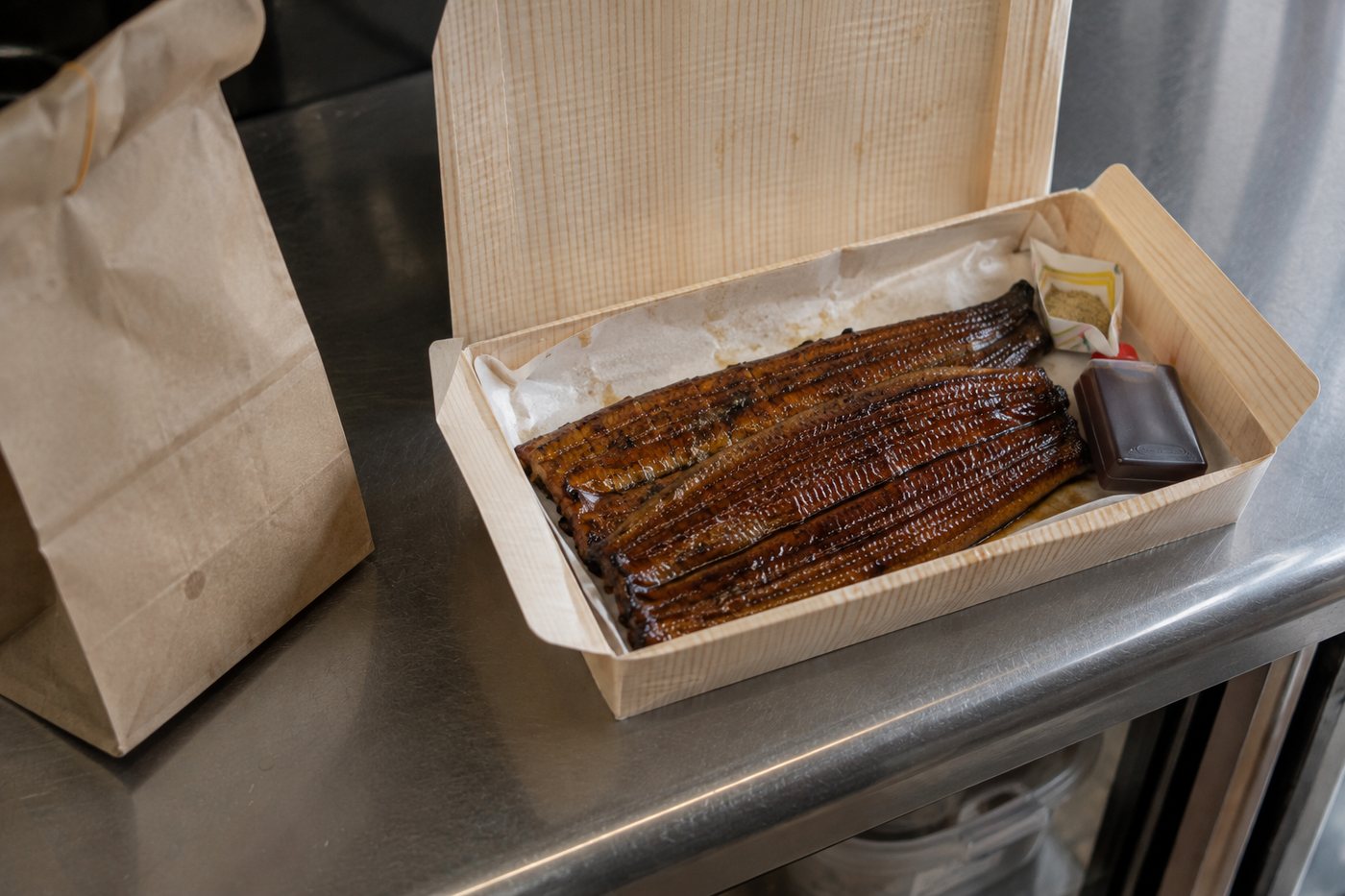 経木の折箱に詰められた蒲焼きとクラフト紙の袋
