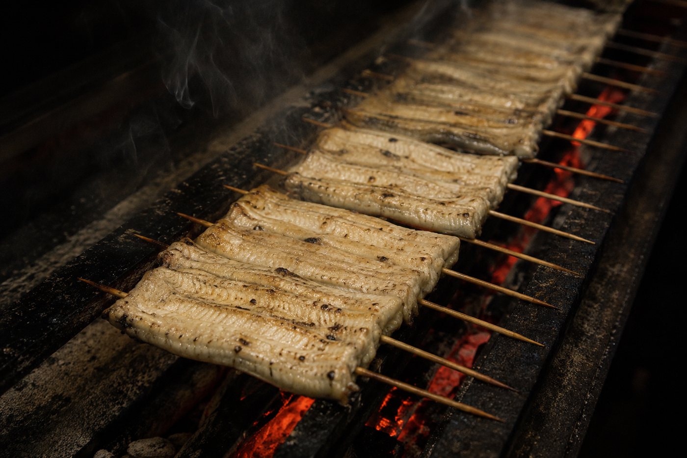竹串を打った白い鰻を炭床で素焼きにするところ